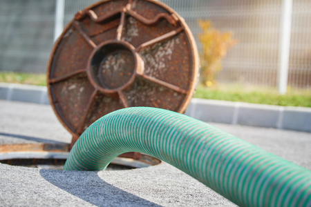 Green pump hose running into an open septic manhole
